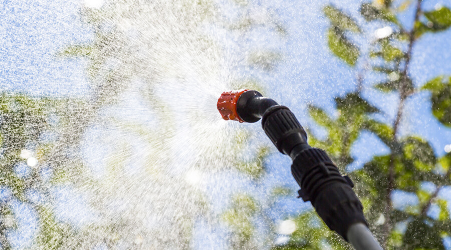 tree-care-and-tree-srapying climber using chainsaw to cut down tree while supported by crane